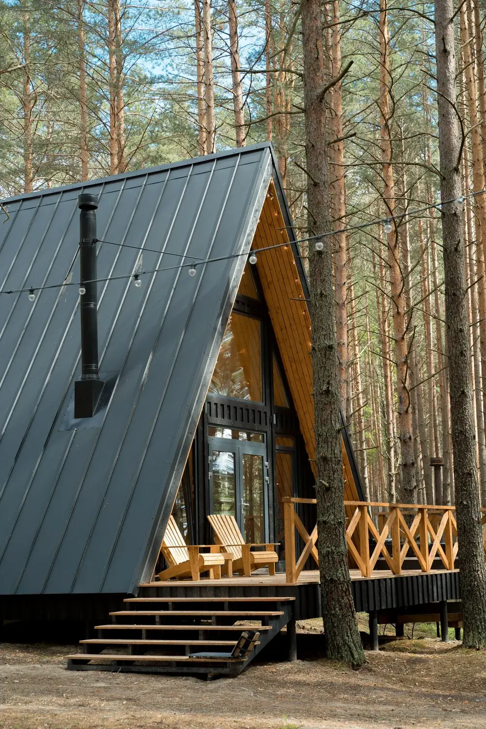 A-frame cabin with a dark standing seam metal roof in a pine forest
