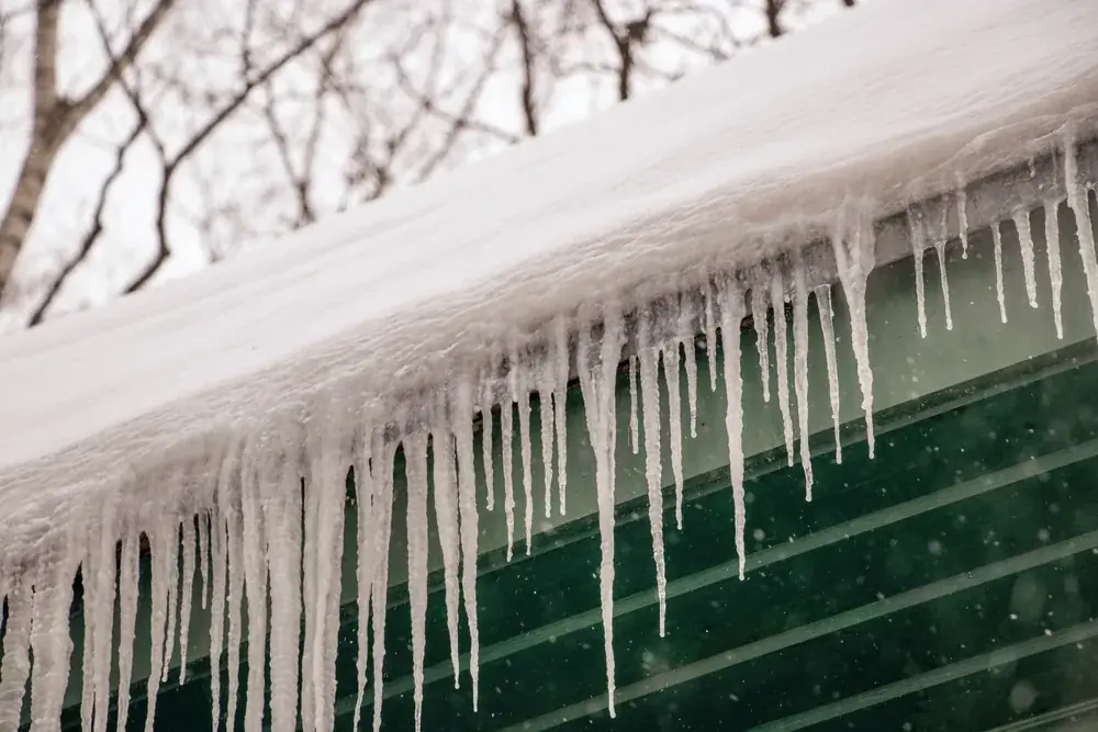 Icicles hanging from the snow-covered eave of a metal roof