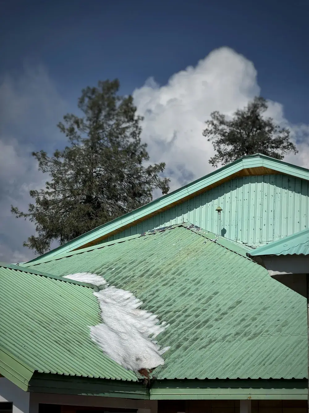 Snow sliding off a green metal roof