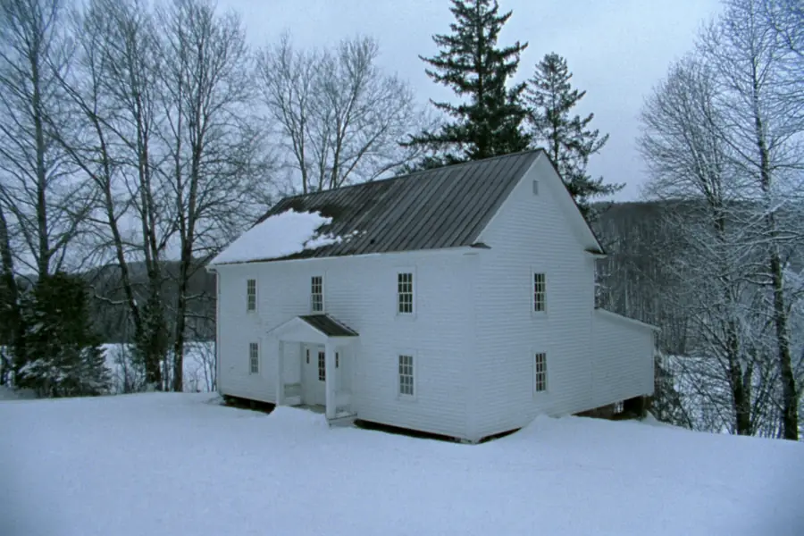 Clapboard farmhouse with a pewter standing seam metal roof under snow near Plattsburgh, New York