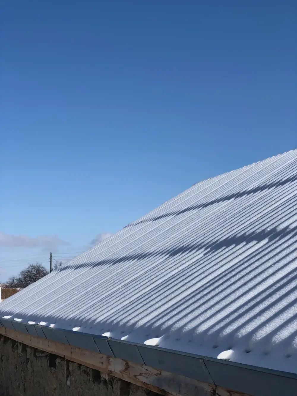 Snow dusting a metal roof under a clear blue winter sky